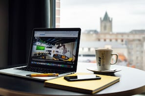 Un ordinateur portable est posé sur une table, avec une tasse et un carnet à côté.