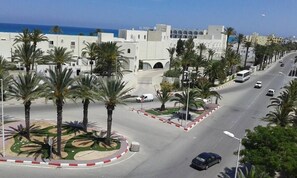 A street with palm trees and a white building with arches. - Residence MahdiaSquare (Mahdia)