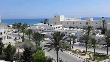 Una zona costera urbana con edificios modernos, palmeras y una vista despejada del mar.