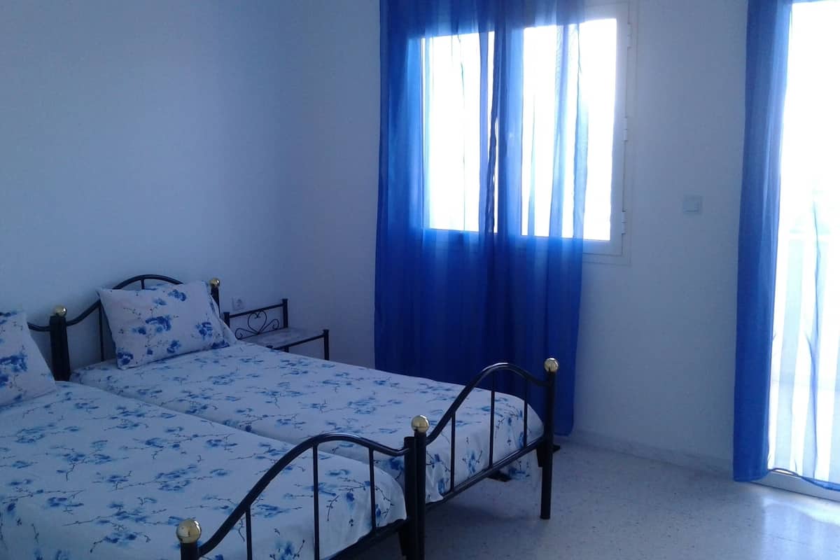 A bedroom with a bed, curtains, and a window.