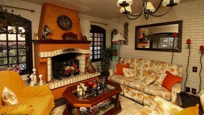 A living room with a fireplace, floral sofa, and yellow armchairs. - Pousada Casa da Colina (Gramado)