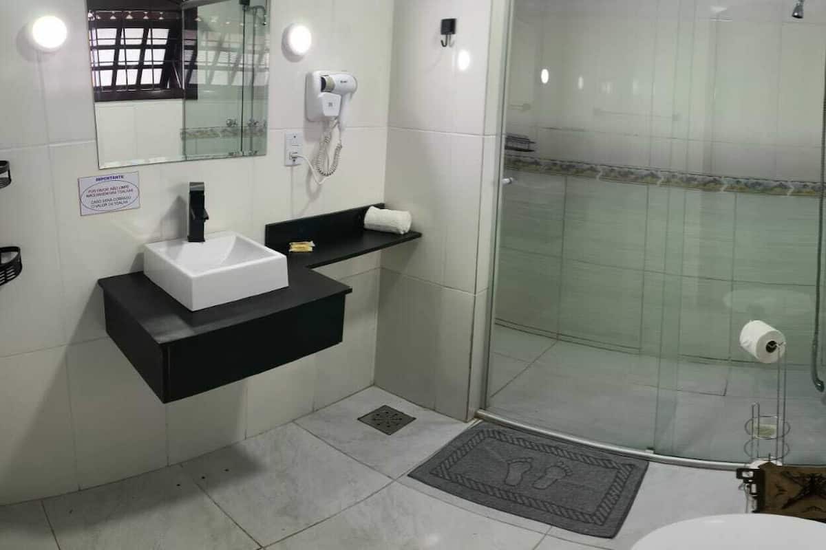 A bathroom with a white sink, black countertop, glass shower enclosure, and a towel rack.