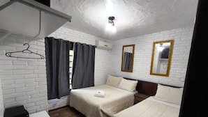 A room with two beds, a white brick wall, a wooden floor, a desk, and a hanging coat rack. - Pousada Casa da Colina (Gramado)