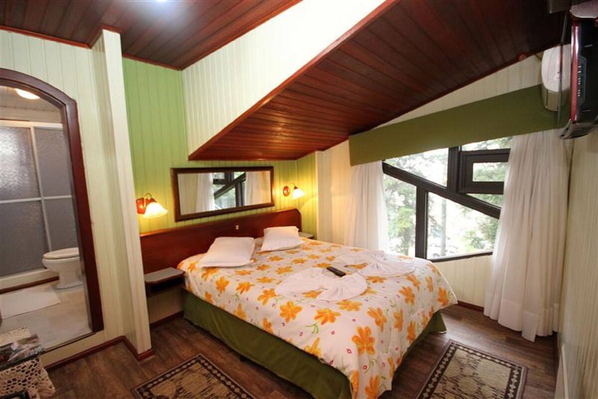 A bedroom with a bed, a window, a mirror, and a ceiling fan.