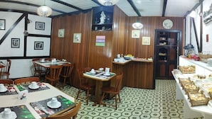 A cozy restaurant with wooden paneling, a tiled floor, and a Christmas-themed table setting. - Pousada Casa da Colina (Gramado)