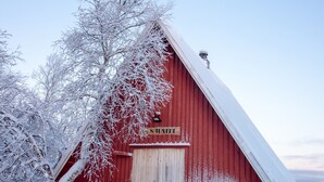 En rød lade med snedækket tag og en trædør.
