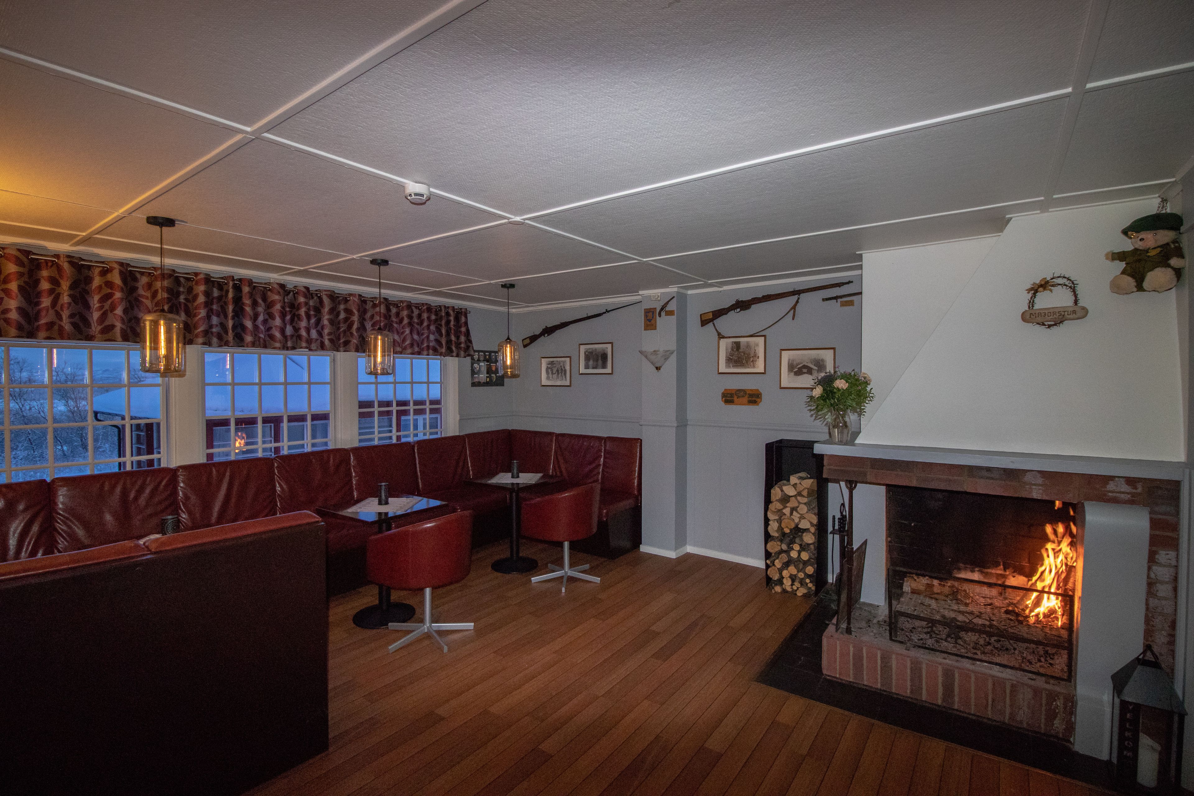 A cozy restaurant with leather booths, a fireplace, and a view of the outside.