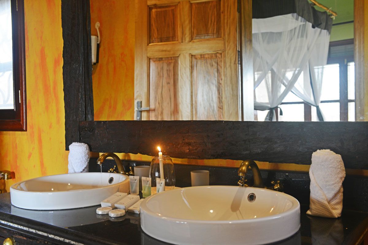 Un baño con dos lavamanos, un espejo y una vela.