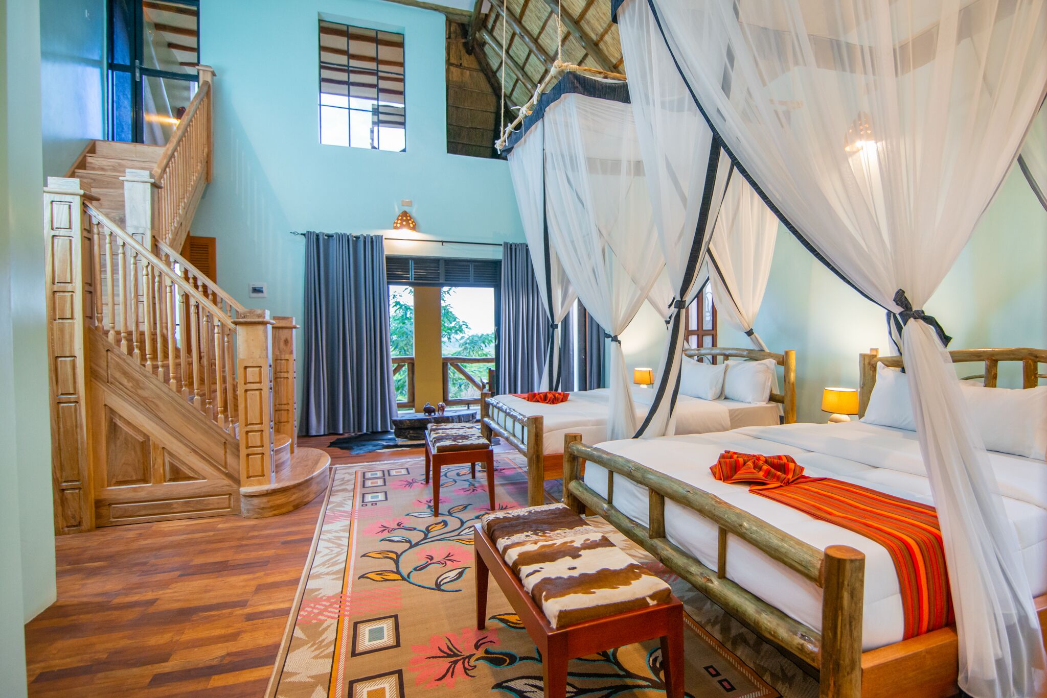 Een slaapkamer met een houten bed, een bankje, een trap en uitzicht op de omgeving.