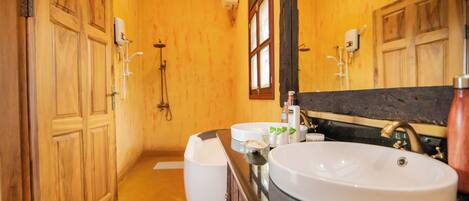 A bathroom with wooden walls, a large mirror, two sinks, and a shower area.