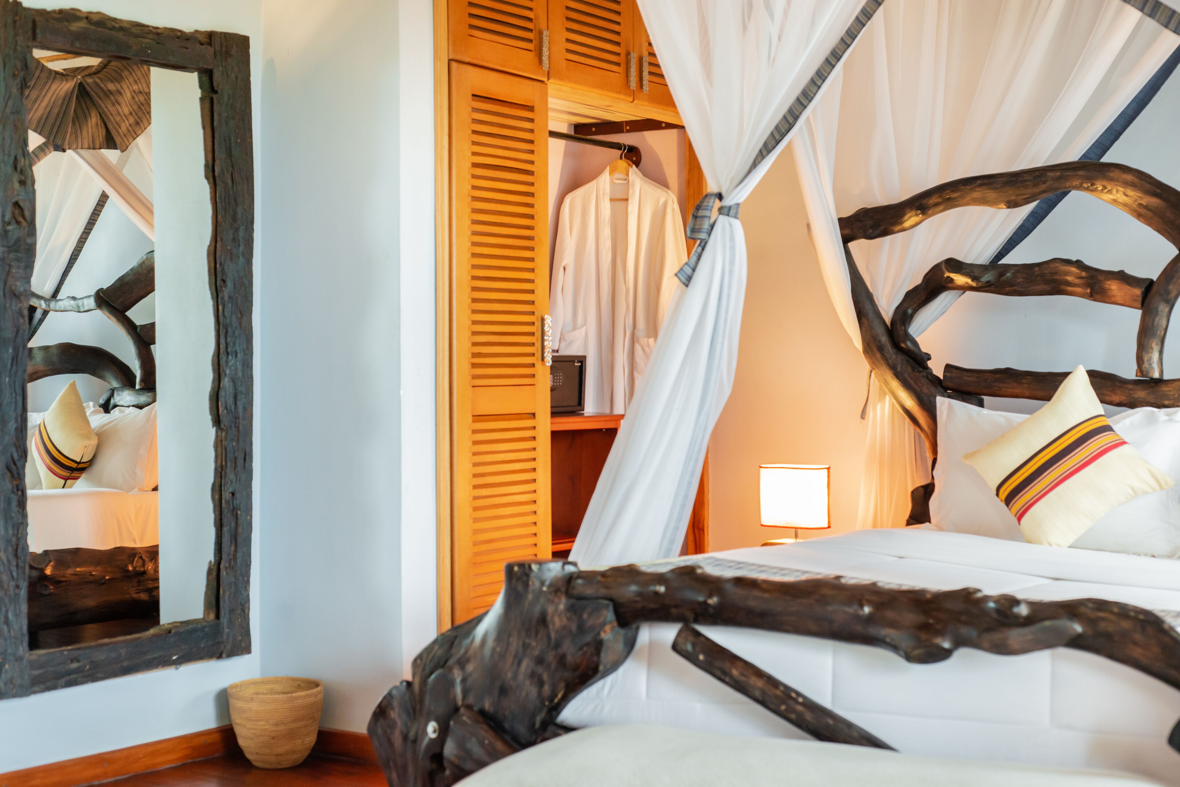 Un dormitorio con cama con dosel, cabecera de madera y un espejo en la pared.