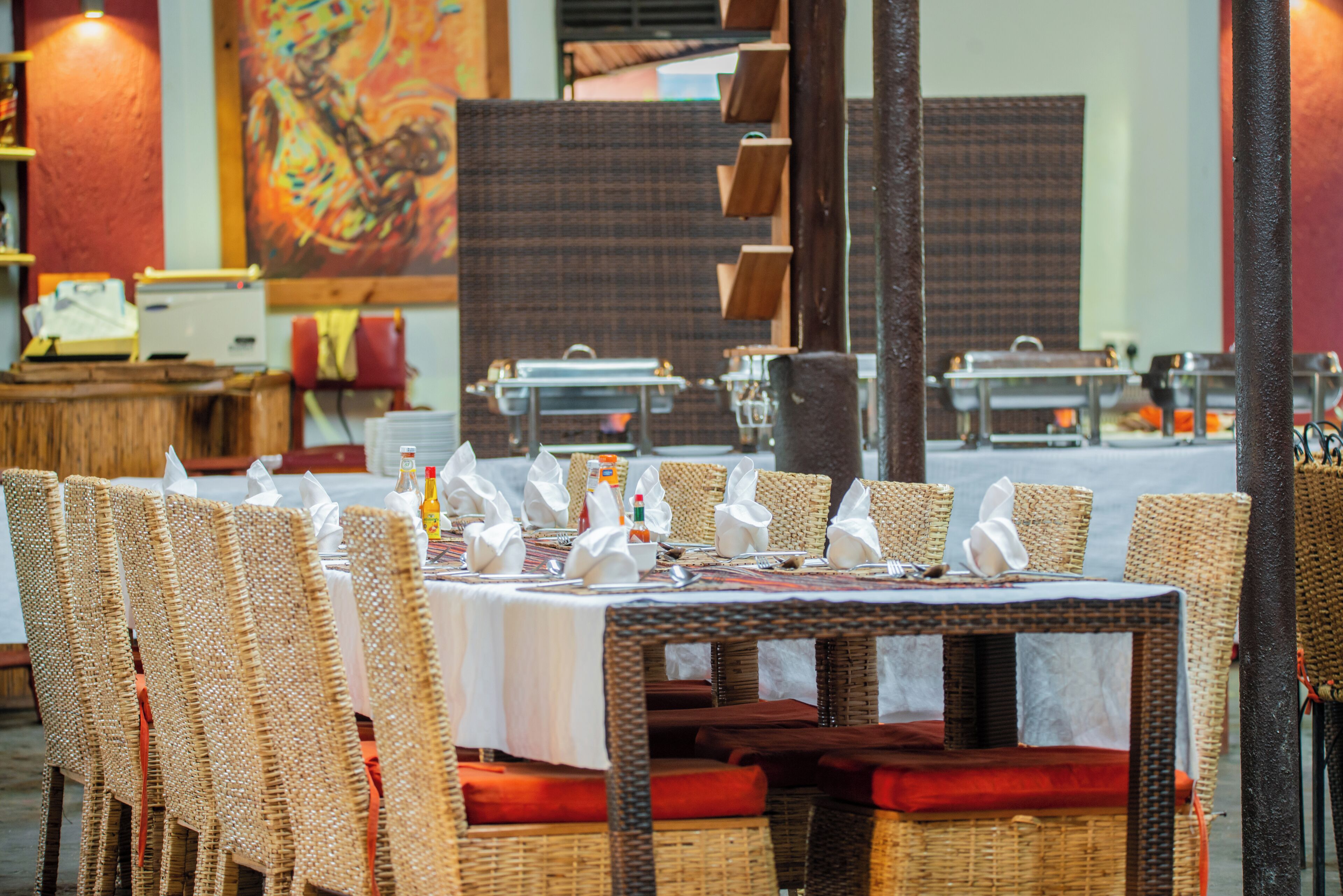 Un restaurant avec des chaises et des tables en osier, disposées pour le service.