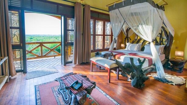 Una habitación amplia con una cama grande, piso de madera, dosel sobre la cama y vistas al exterior.