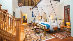 Una habitación con una escalera de madera, una cama con dosel, un banco y un tapete estampado.