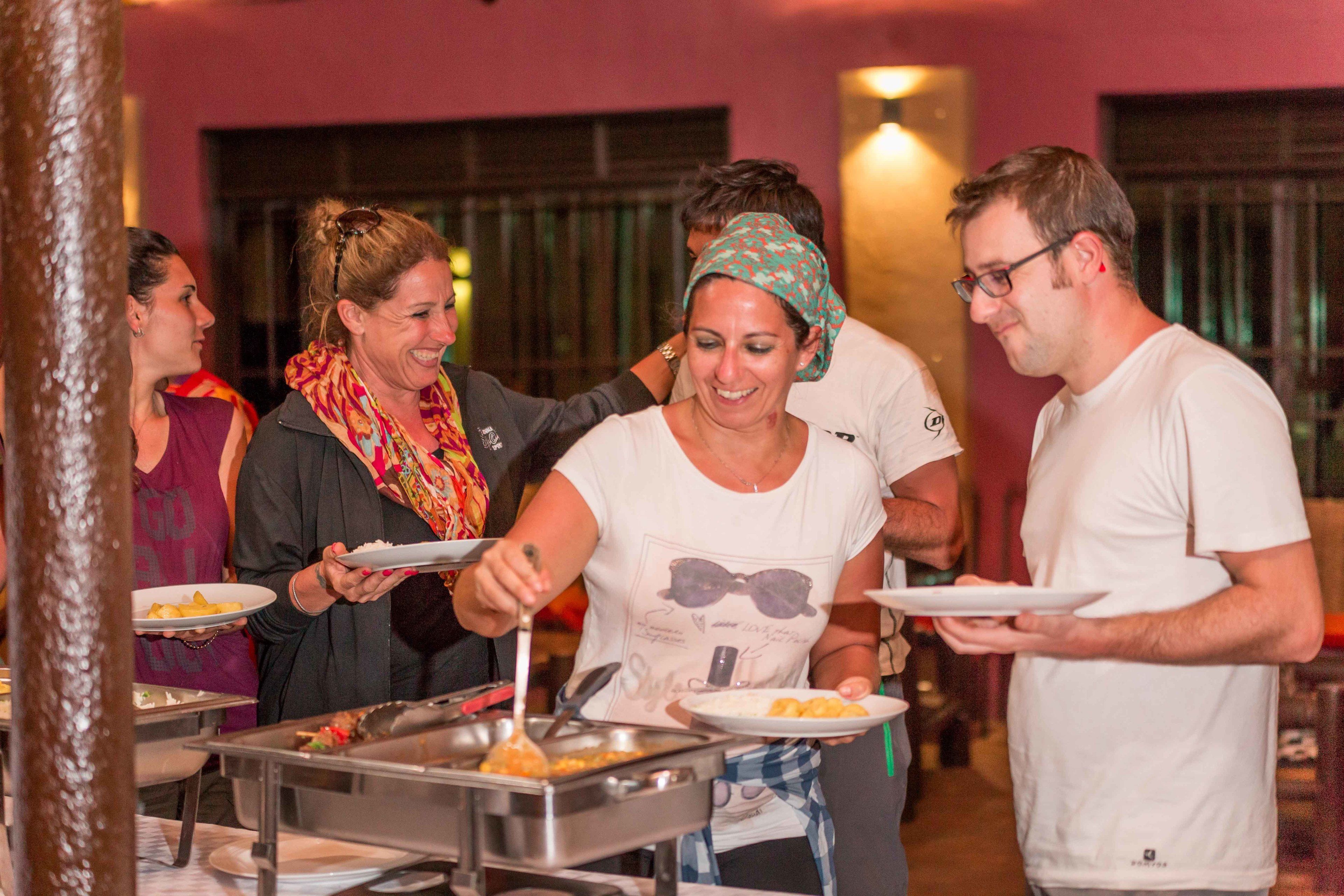 A group of people at a buffet with various food items and serving utensils.