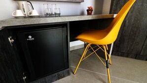 A compact kitchen with a built-in refrigerator, a countertop, and a yellow chair. - Gold Lion Residensea (St. Julian's)