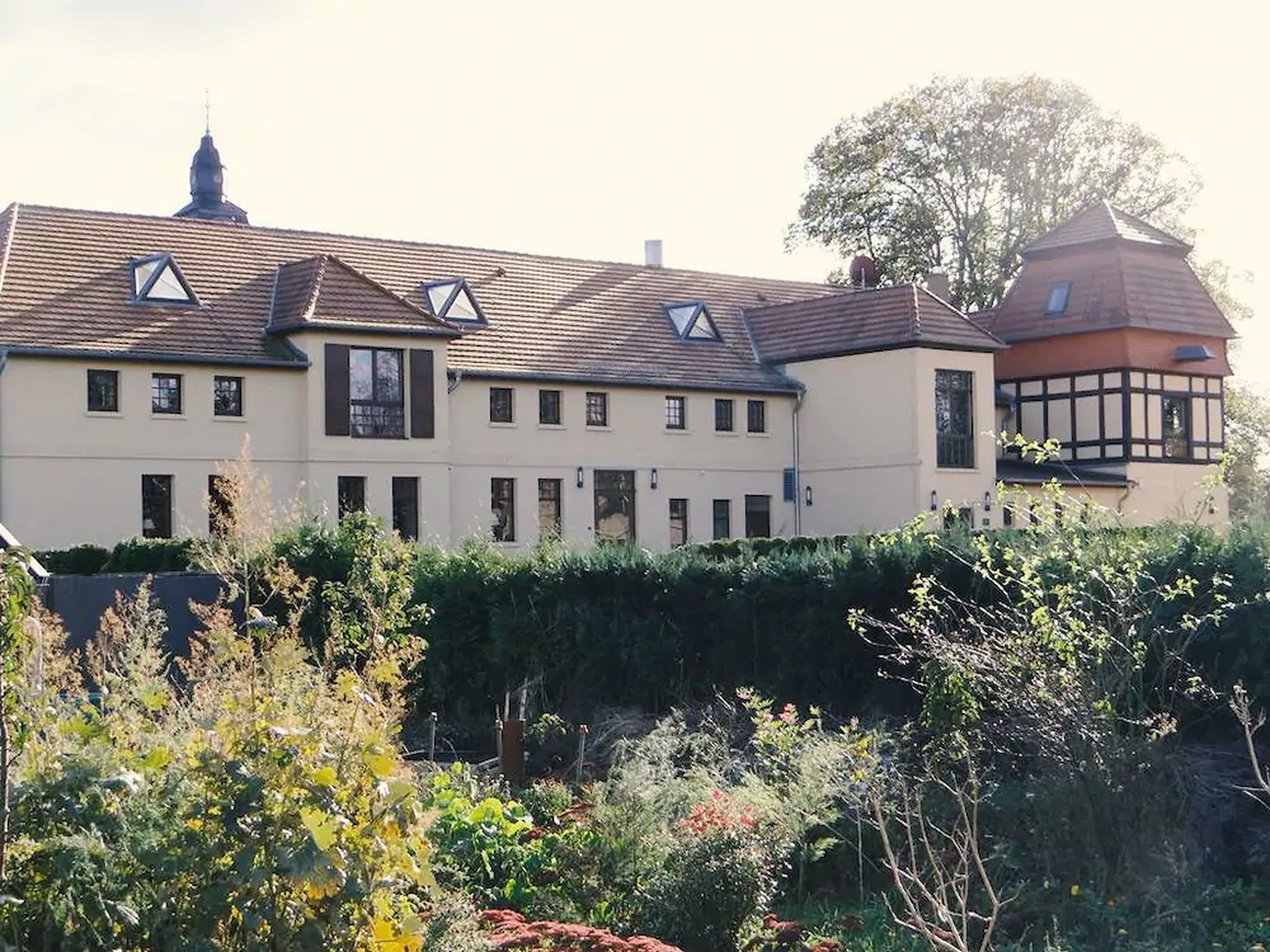 A large, multi-story building with a symmetrical facade, multiple windows, and a prominent tower with a pointed roof.