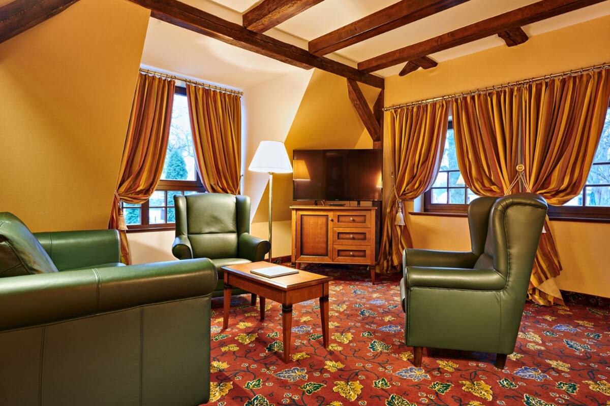 Une pièce avec un plafond en bois, des canapés en cuir vert, un meuble en bois et un tapis à motifs.