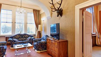 A living room with a sofa set, a wooden cabinet, a mounted deer head, and a television.