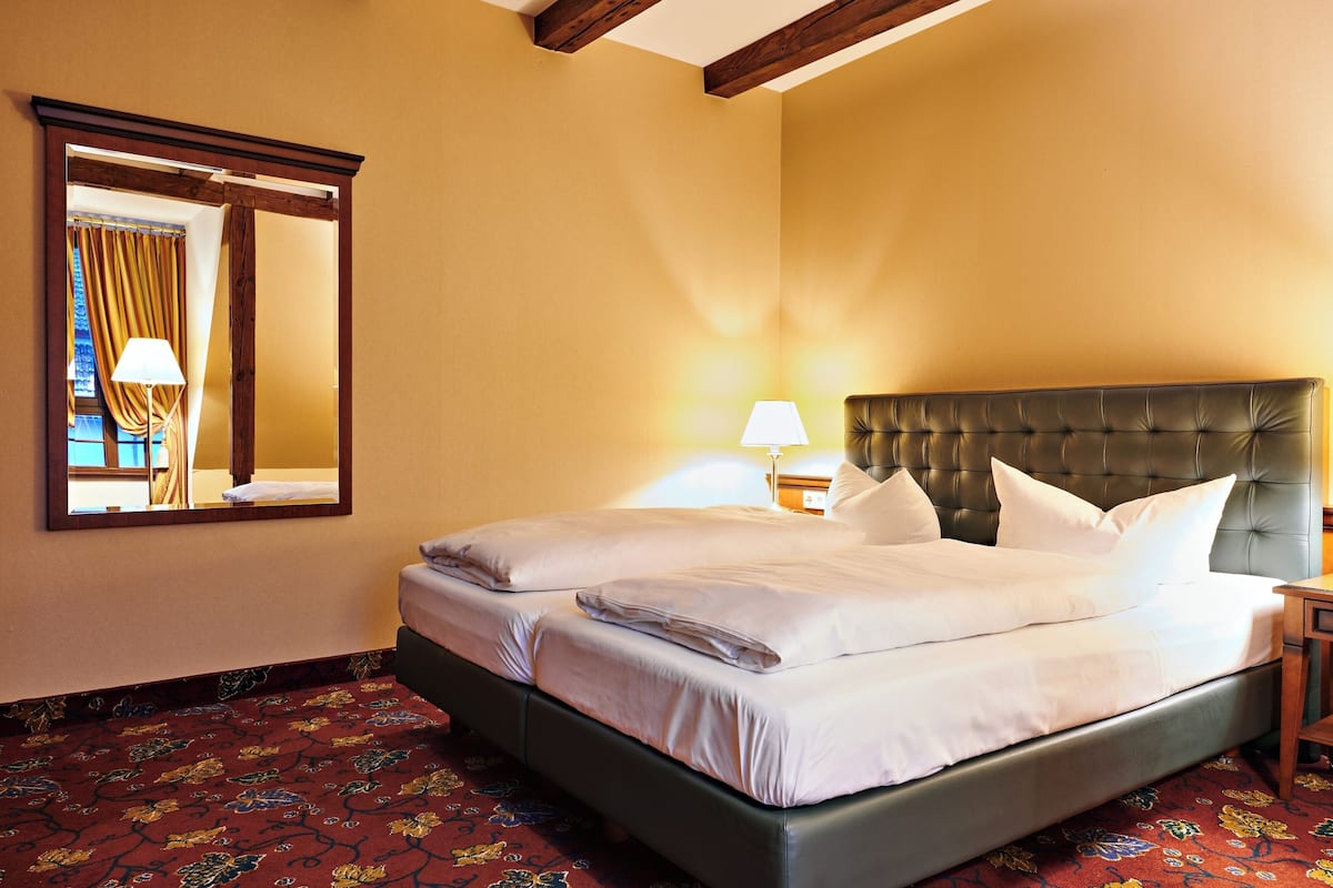 Une chambre d’hôtel avec un grand lit, un miroir, une table de chevet et une lampe.