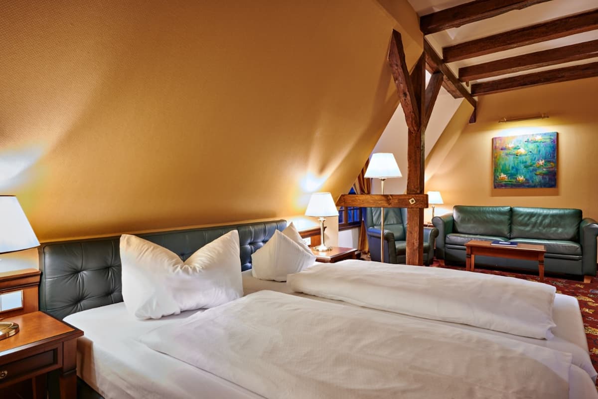 Une chambre d’hôtel avec un grand lit, un canapé vert et un tableau accroché au mur.