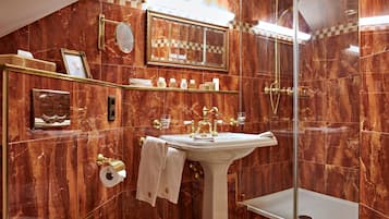 Ein Badezimmer mit Marmorwand, einem Standwaschbecken, einer Glasdusche und einem Waschtisch mit Ablageflächen.