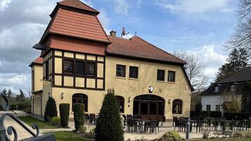 Un edificio tradicional con un letrero que dice "CHEVAL BLANC" y mesas al aire libre.