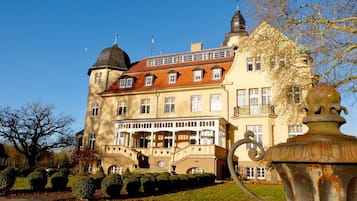 Un grand bâtiment historique doté de nombreuses fenêtres, d’un escalier central et d’une tour saillante.