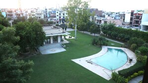 A residential area with a swimming pool, a lawn, and a building with a flat roof. - Anantkoti Hotel (New Delhi)