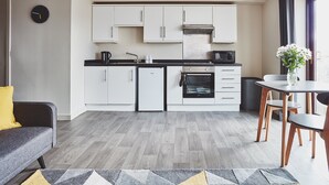 Une cuisine moderne avec des meubles blancs, un four encastré et un coin repas comprenant une table et des chaises.