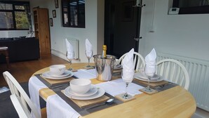 A dining table set with white tableware, a champagne bottle, and a silver ice bucket. - Warren Cottage (Norwich)