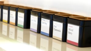 Une rangée de récipients noirs, chacun portant une étiquette indiquant la variété de thé qu'il contient.