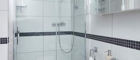 A modern bathroom with a glass-enclosed shower, a white sink, and a mirror above it.