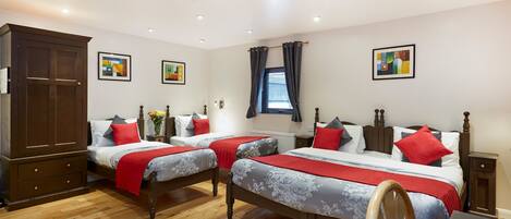 A hotel room with two single beds, a wooden wardrobe, a desk, and a chair.