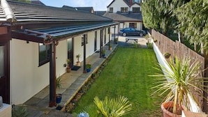Une propriété résidentielle dotée d’un patio couvert, d’une pelouse bien entretenue et d’une voiture garée.