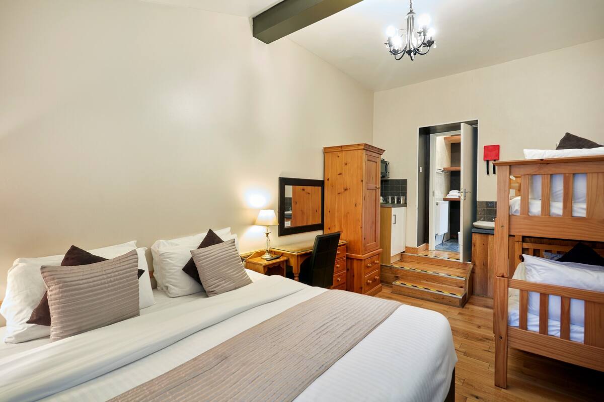 Ein Hotelzimmer mit einem großen Bett, einem Schreibtisch, einem Kleiderschrank und einer Treppe zu einer oberen Etage.