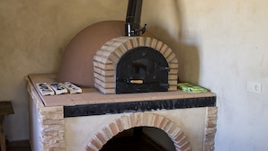 Un four à pizza extérieur en briques, doté d’une cheminée, d’un plan de travail et d’une petite boîte verte sur le dessus.