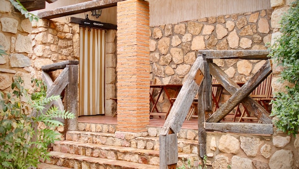 Un bâtiment en pierre avec un escalier en bois menant à un espace abrité équipé de sièges.