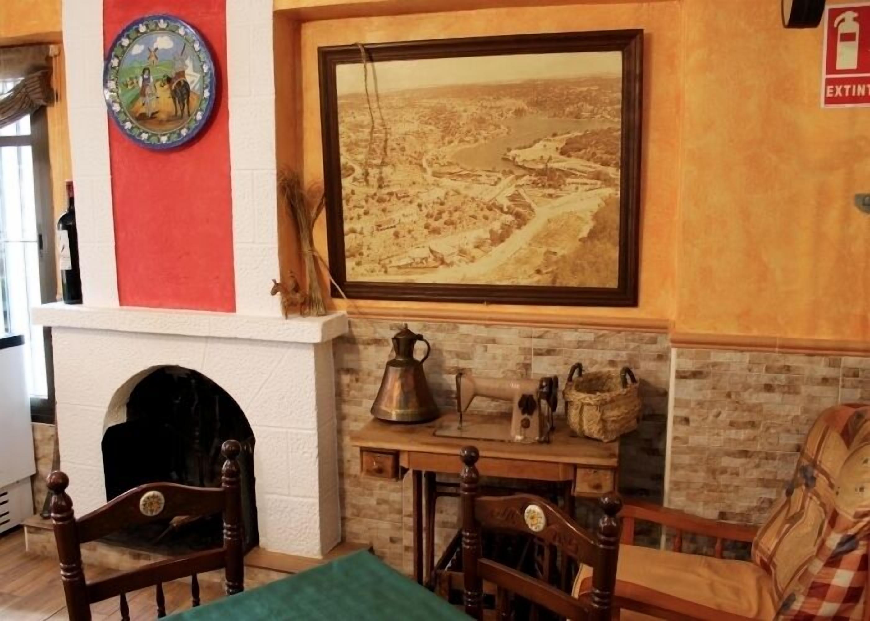 Une pièce chaleureuse avec une cheminée, un tableau historique encadré et un décor rustique.