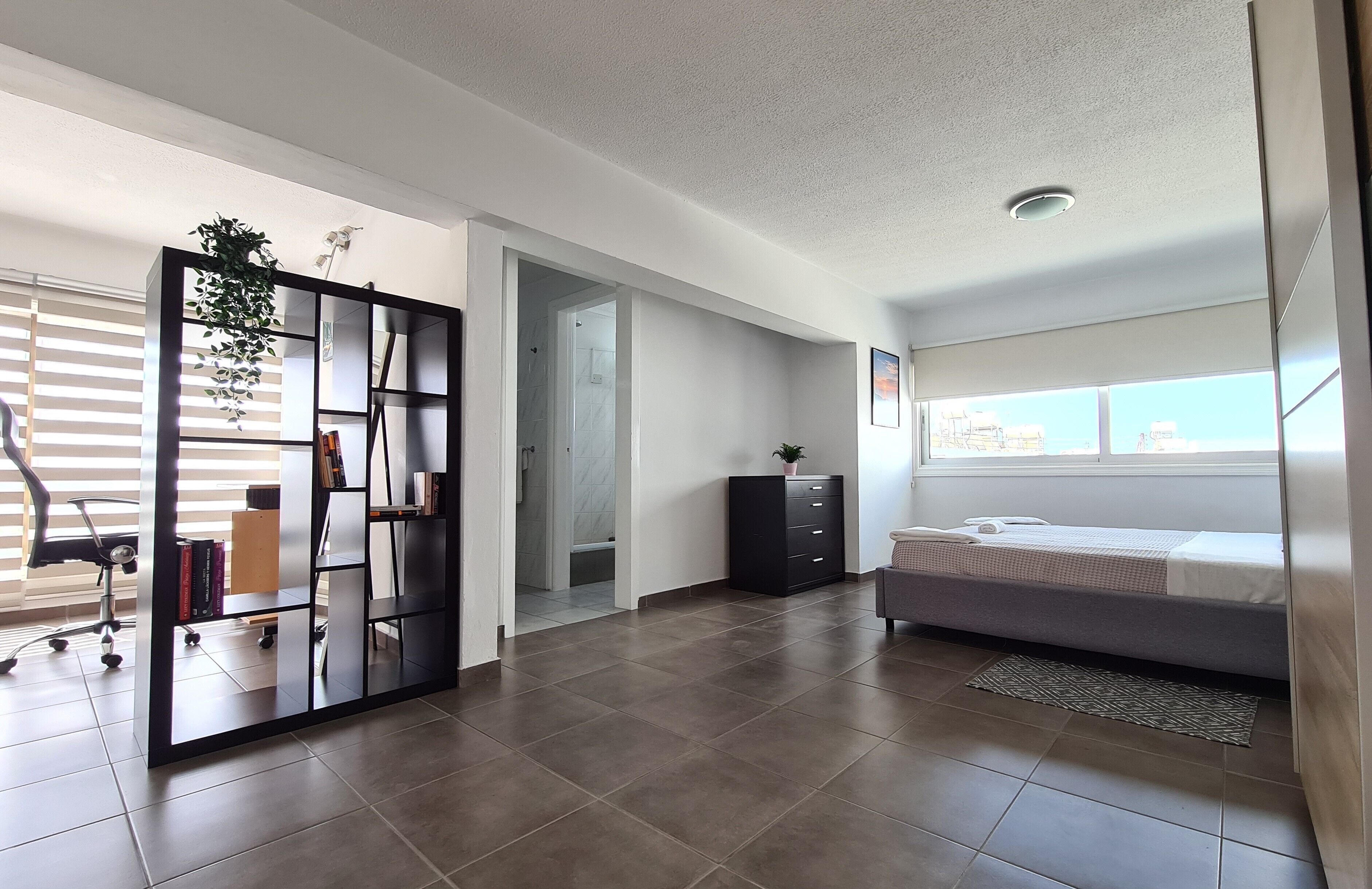 Un dormitorio moderno con cama, escritorio y estantería.