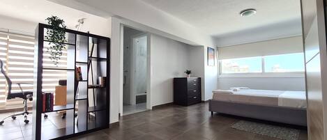 A modern bedroom with a bed, a desk, and a bookshelf.