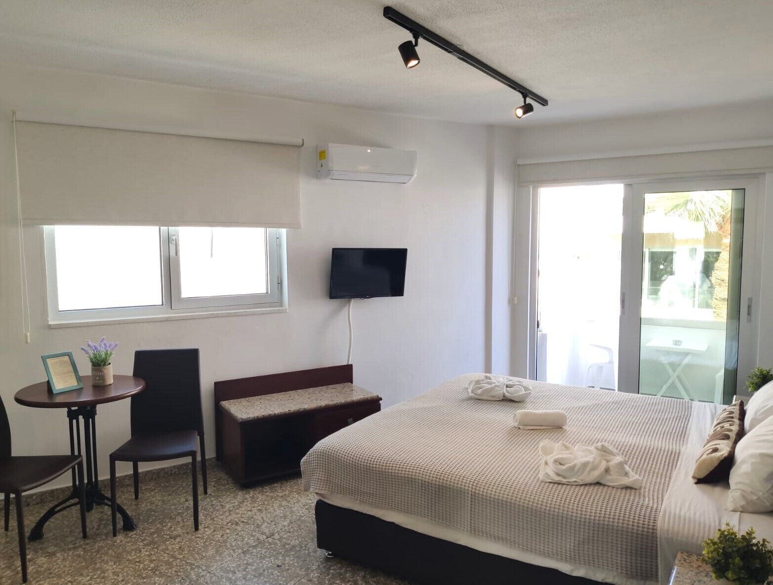 Ein Hotelzimmer mit Bett, Schreibtisch, Stuhl, Fernseher und Fenster.