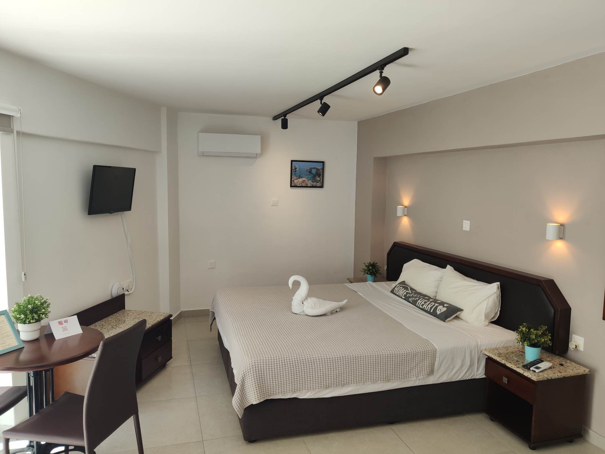 Ein Hotelzimmer mit einem Bett, einem Schreibtisch, einem Stuhl, einem Fernseher und einer Wandklimaanlage.