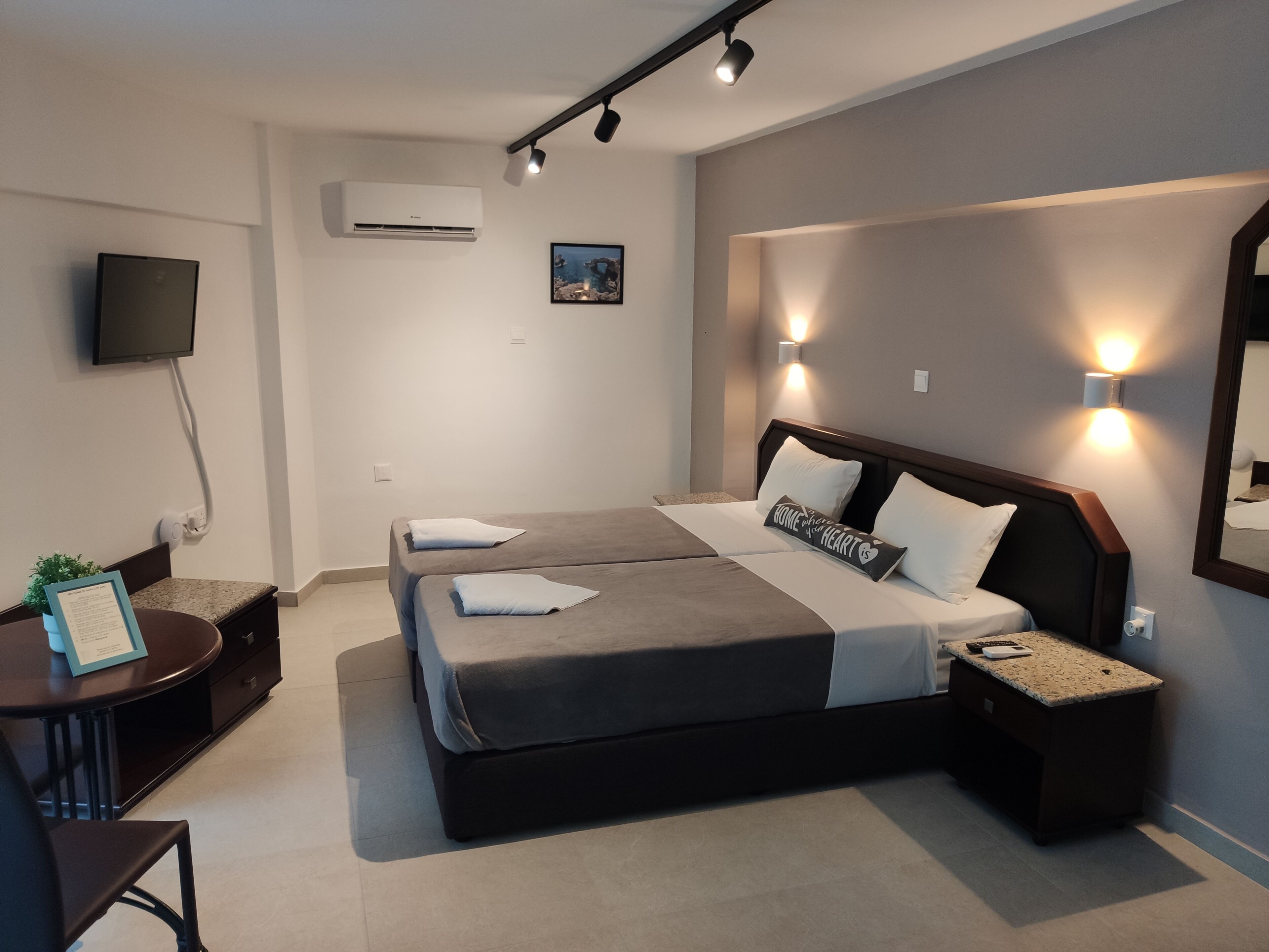 Een moderne hotelkamer met een groot bed, nachtkastjes, een bureau en een flatscreen-tv.