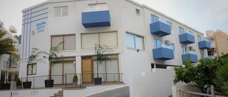 A modern multi-story building with balconies, a staircase leading to the entrance, and a sign reading "NAPA CITY APOTHECARY."