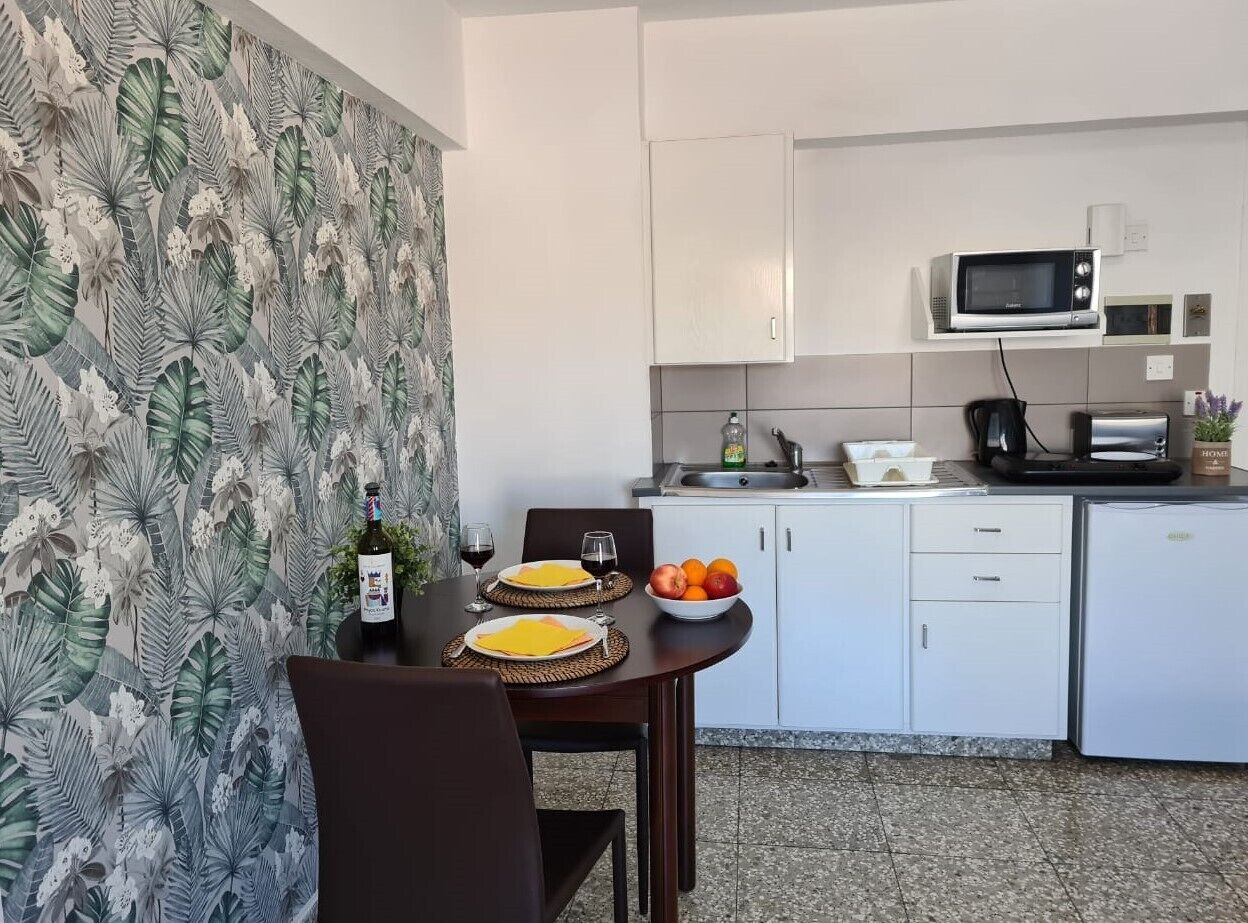 A compact kitchen with white cabinets, a microwave, and a dining area with a table set for two.