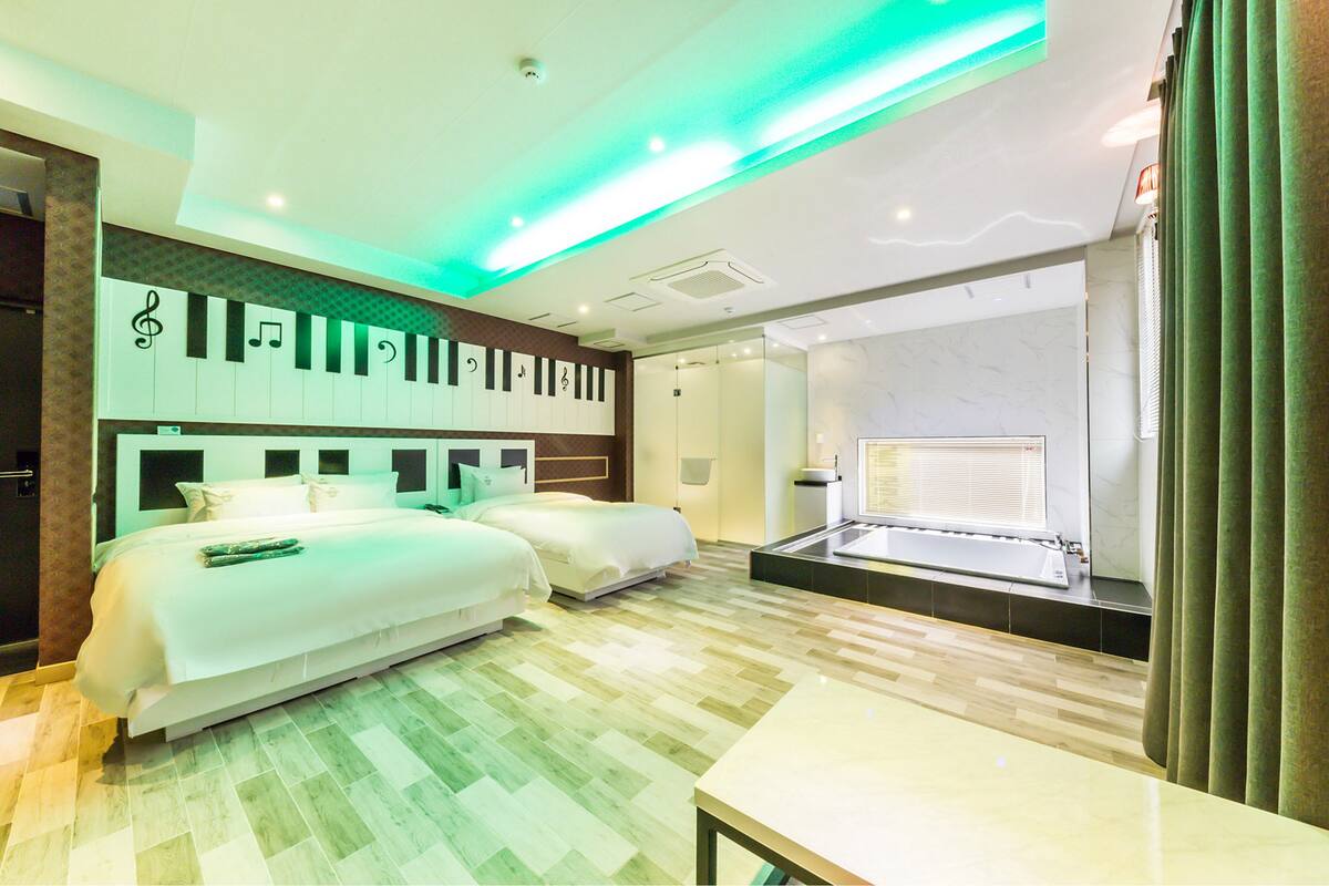 A hotel room with a large bed, a small table, and a window with curtains.