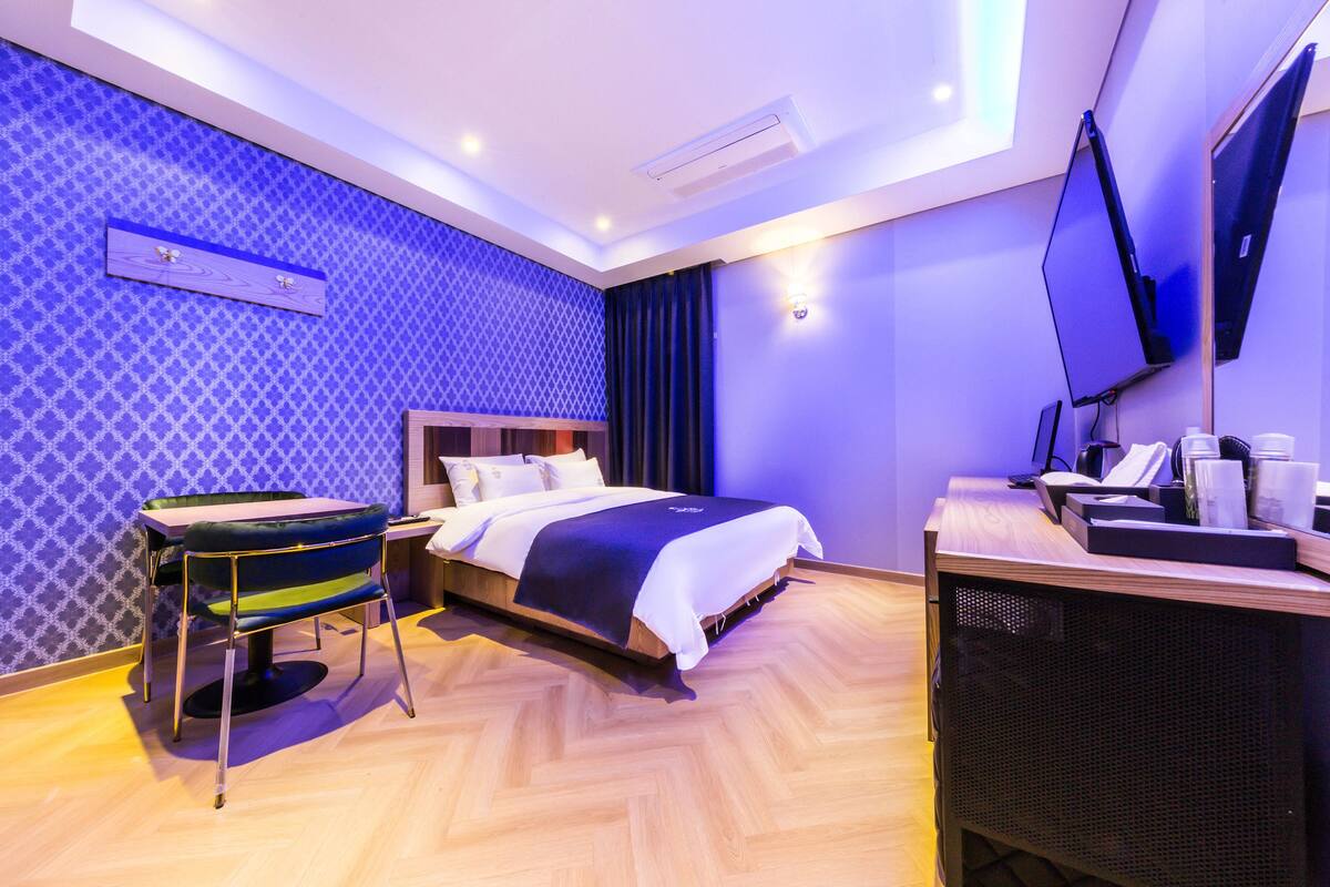 A modern hotel room with a bed, a desk, and a TV.