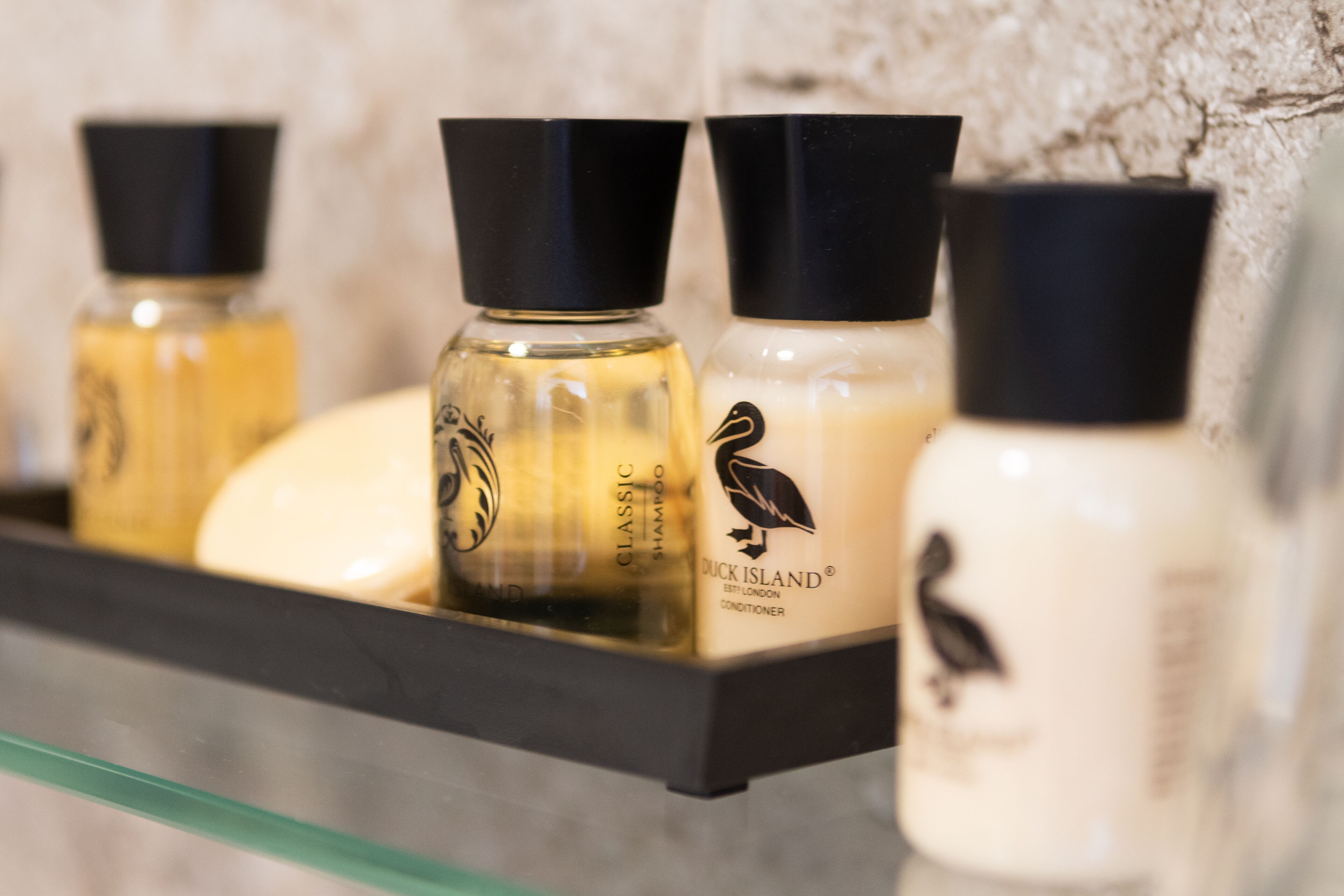 Un estante con tres botellas de Champú y acondicionador Duck Island Classic.