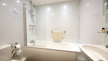 Et moderne badeværelse med et glasafskærmet brusebad, et hvidt badekar, en vask og et toilet.